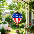 American flag hot air balloon solar lantern hanging beside a flower garden porch