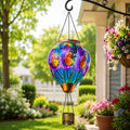 Hand-painted butterfly hot air balloon solar lantern hanging beside a flower-filled garden porch